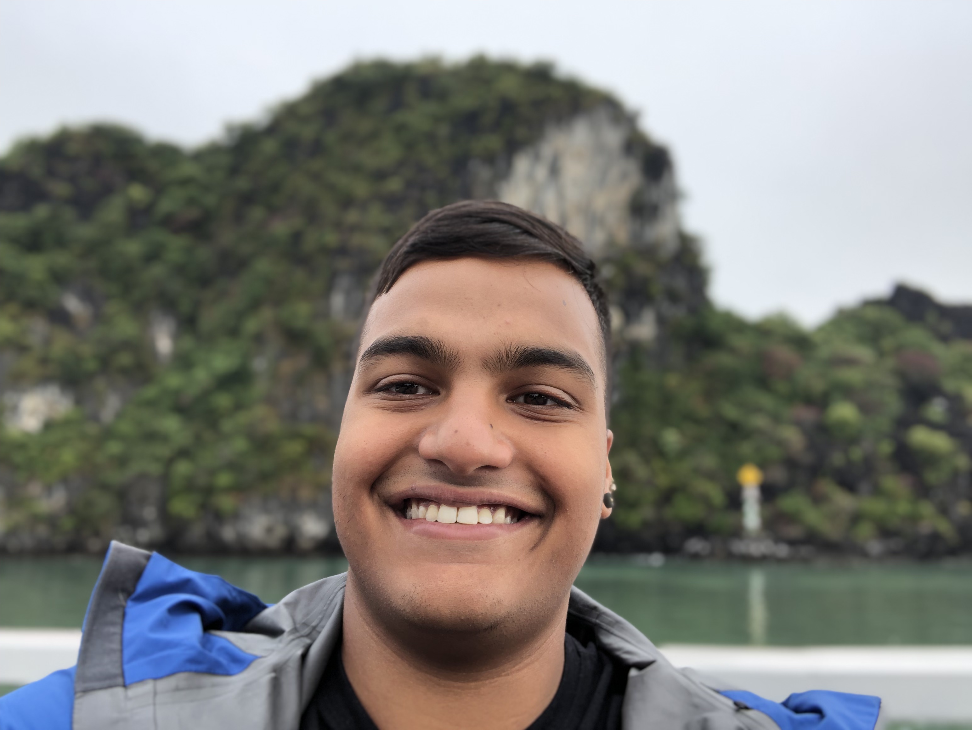 A picture of me on a ship in front of a railing in Ha Long Bay, Vietnam.